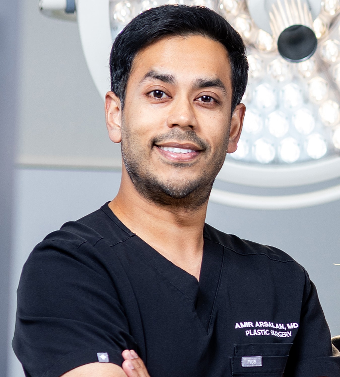 Smiling plastic surgeon in surgical scrubs.