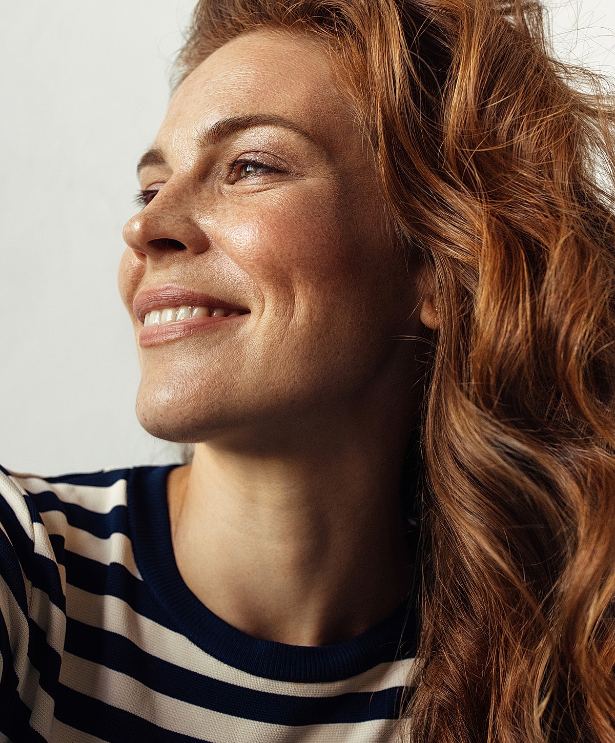 Smiling woman with wavy red hair.