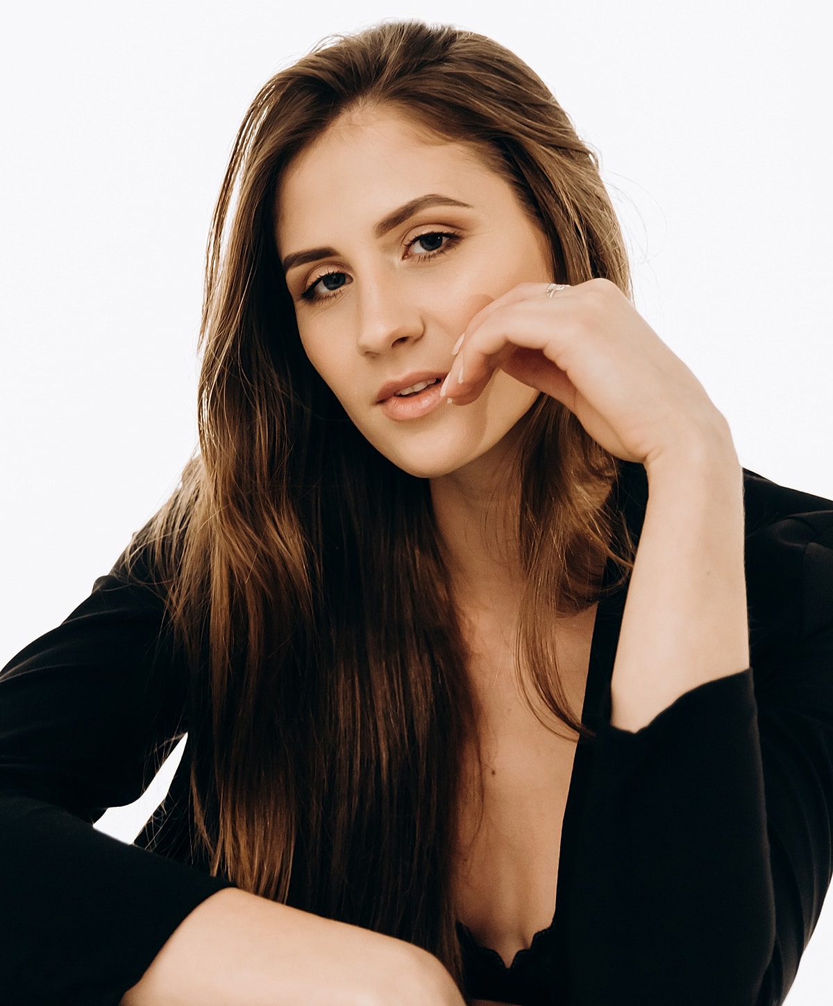 Woman with long hair, thoughtful expression, black outfit.