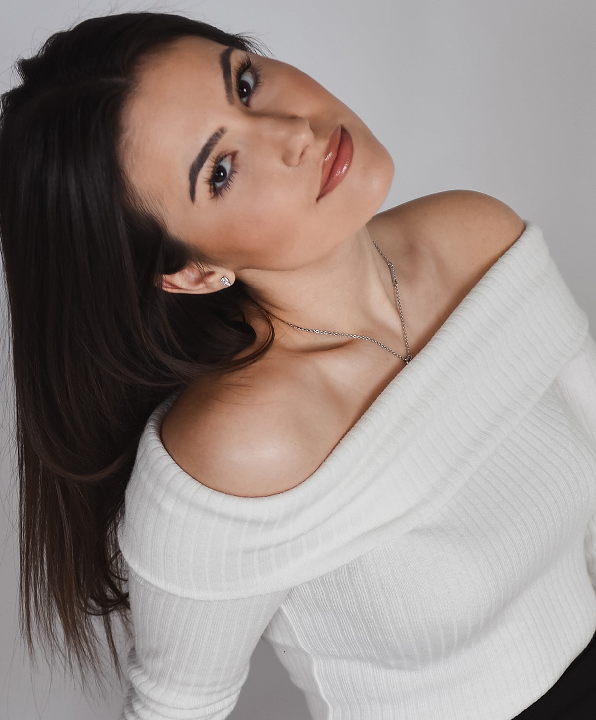 Woman in off-shoulder white sweater, smiling.
