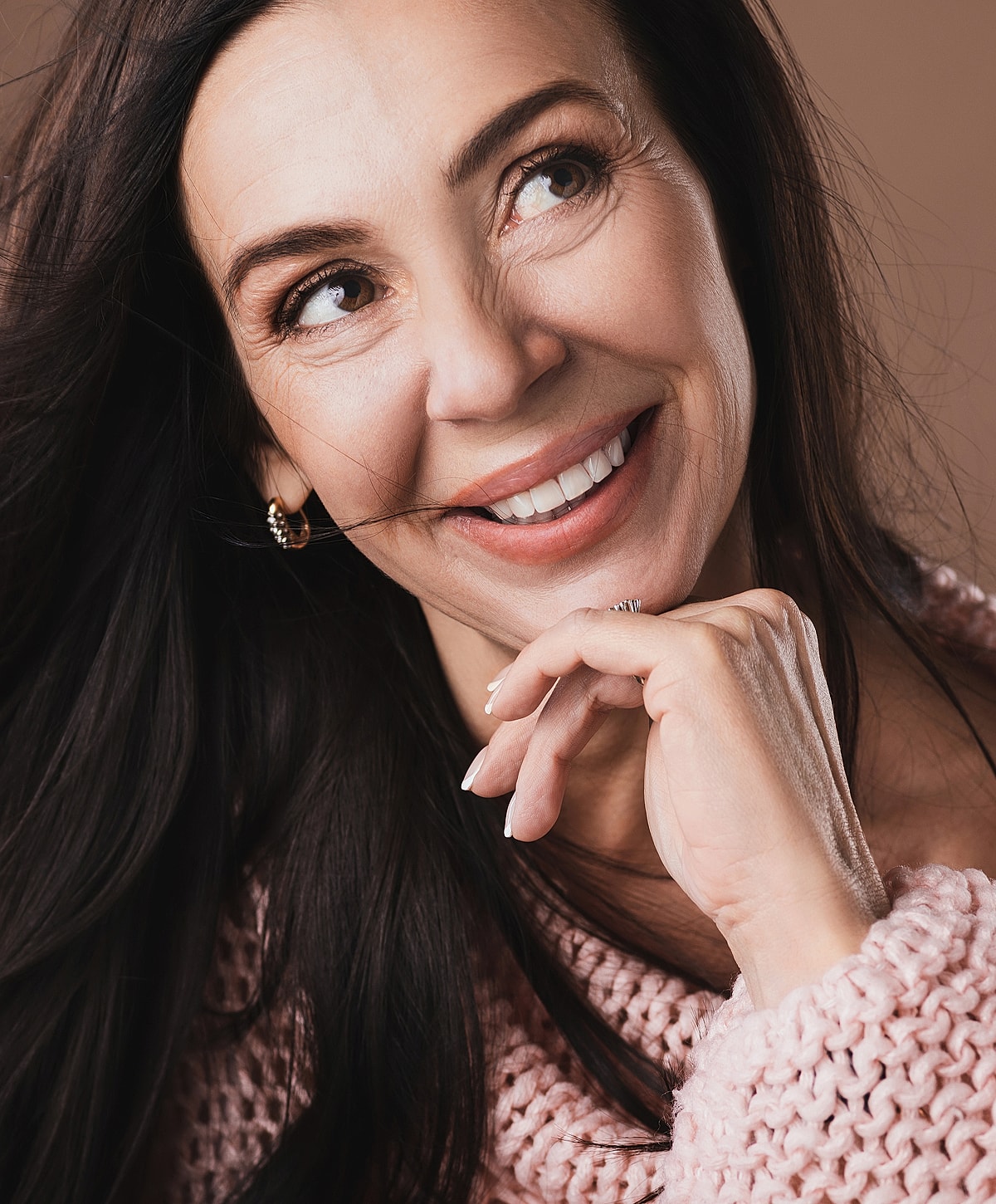 Smiling woman with long hair in cozy sweater.