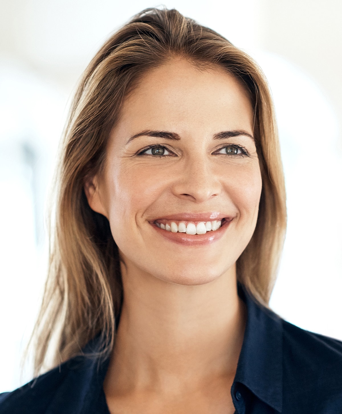 Smiling woman with long hair and blue shirt.