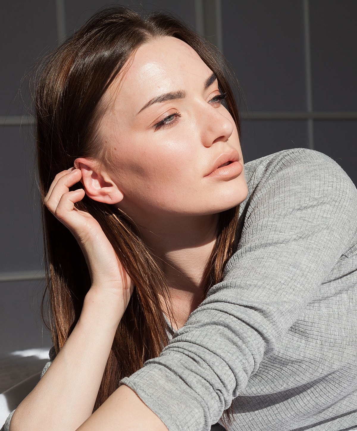 Woman enjoying sunlight with soft expression.