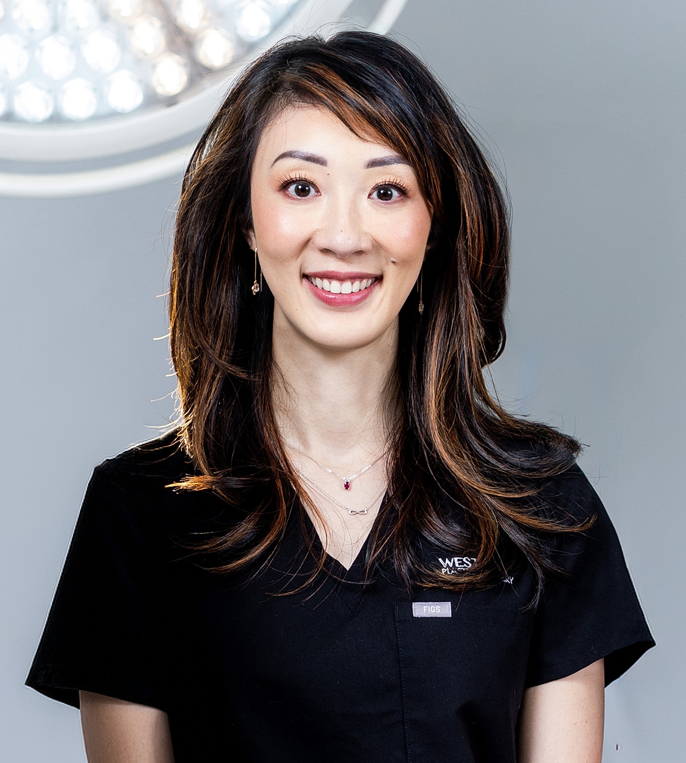 Surgeon in scrubs with surgical lights background.