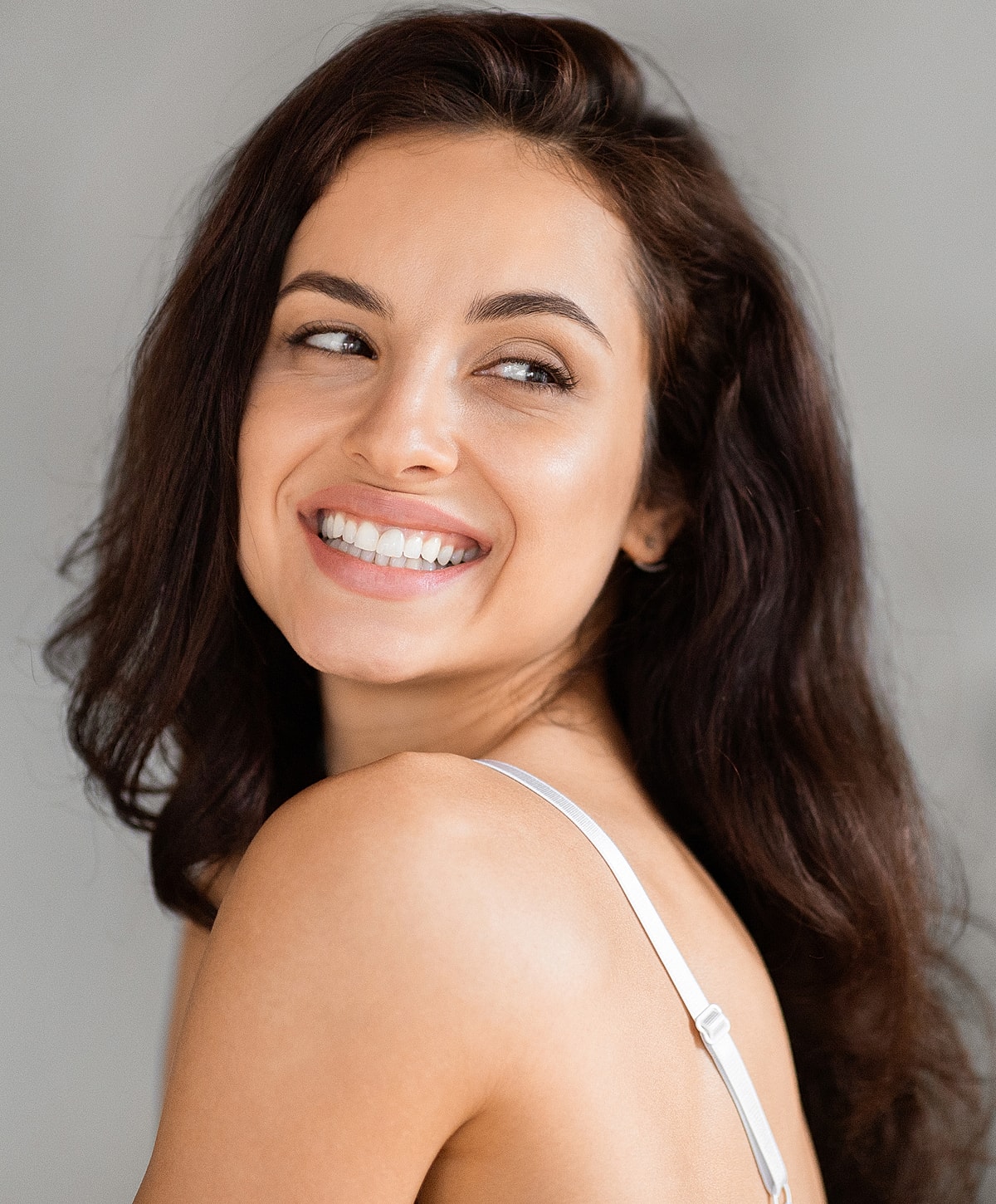 Smiling woman with long, wavy brown hair.