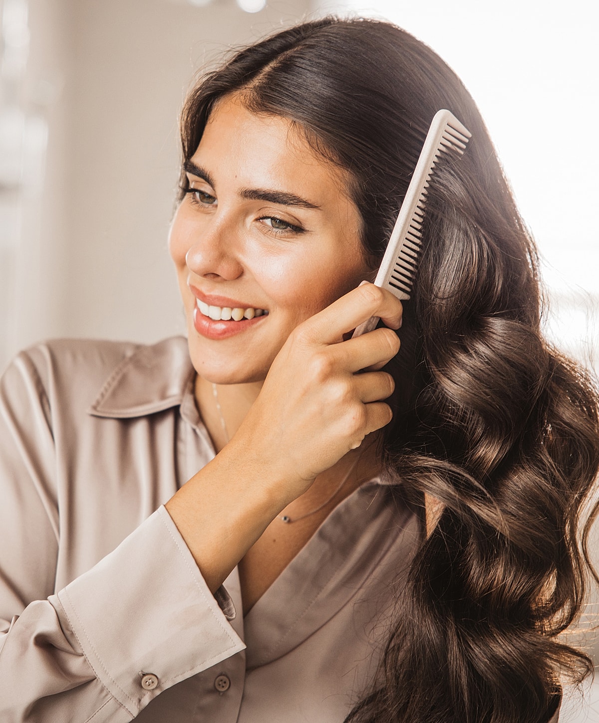 Woman styling her long, wavy hair with comb.