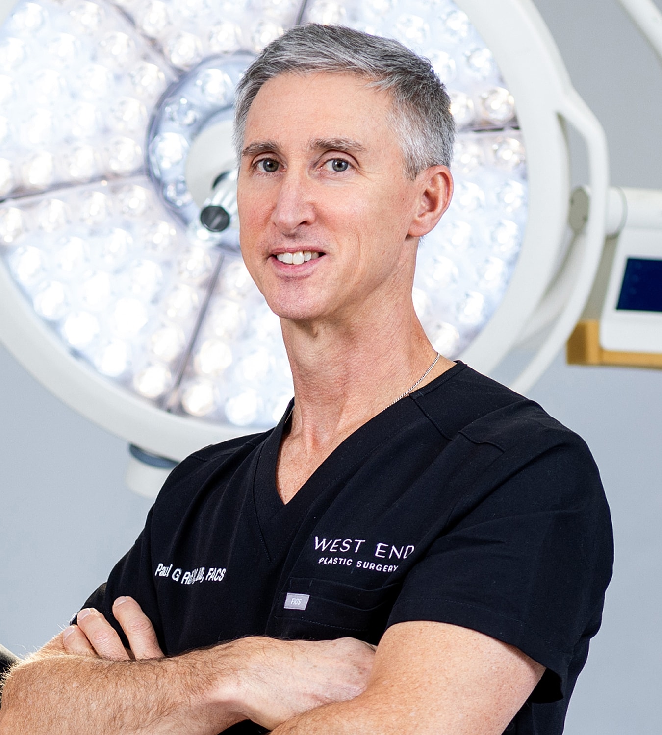 Surgeon in scrubs with surgical lights background.