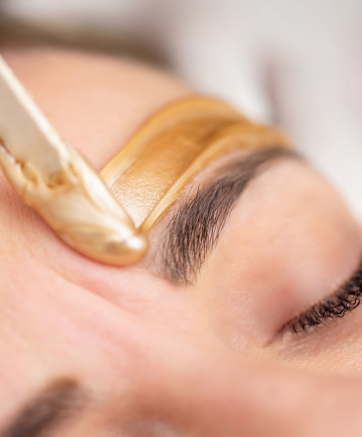 Eyebrow waxing treatment in progress.