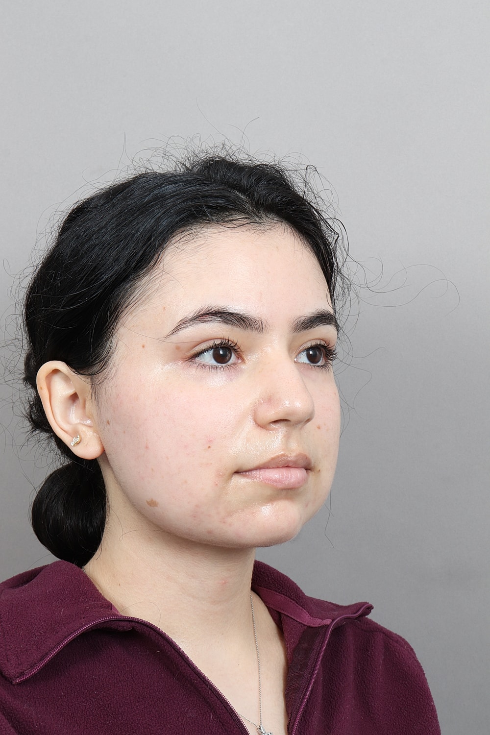 Woman's profile with natural makeup, neutral background.