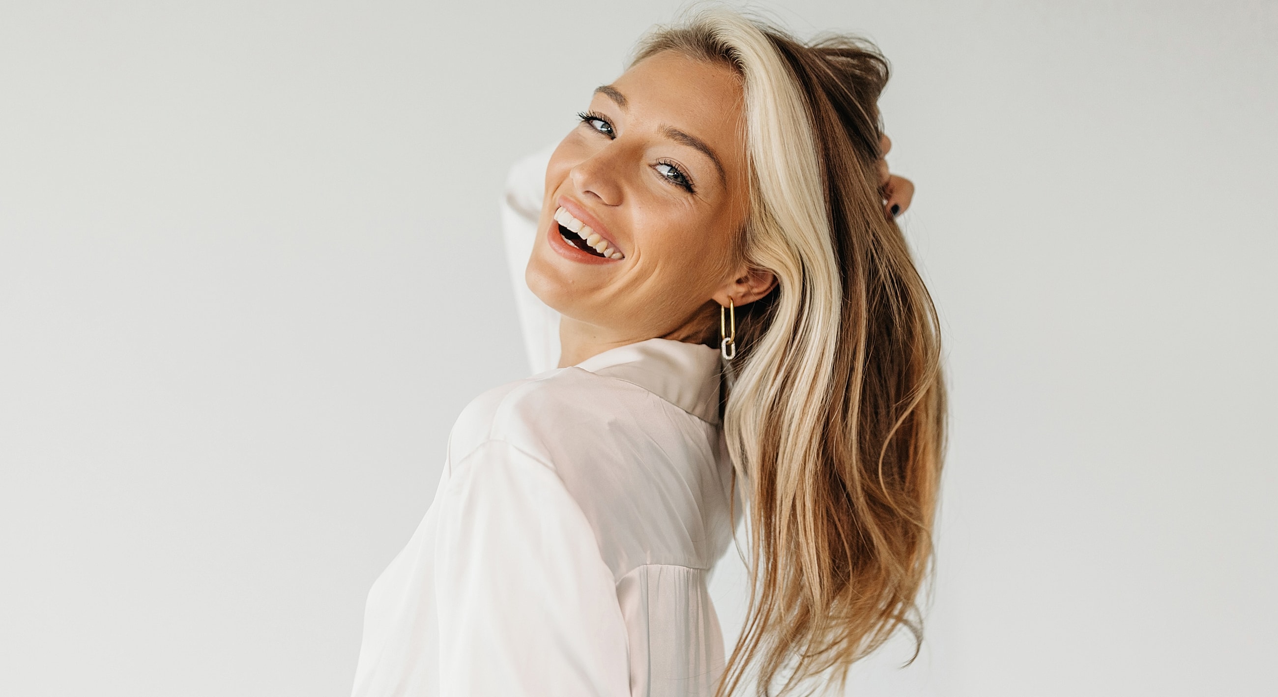 Smiling woman with long hair against neutral background.