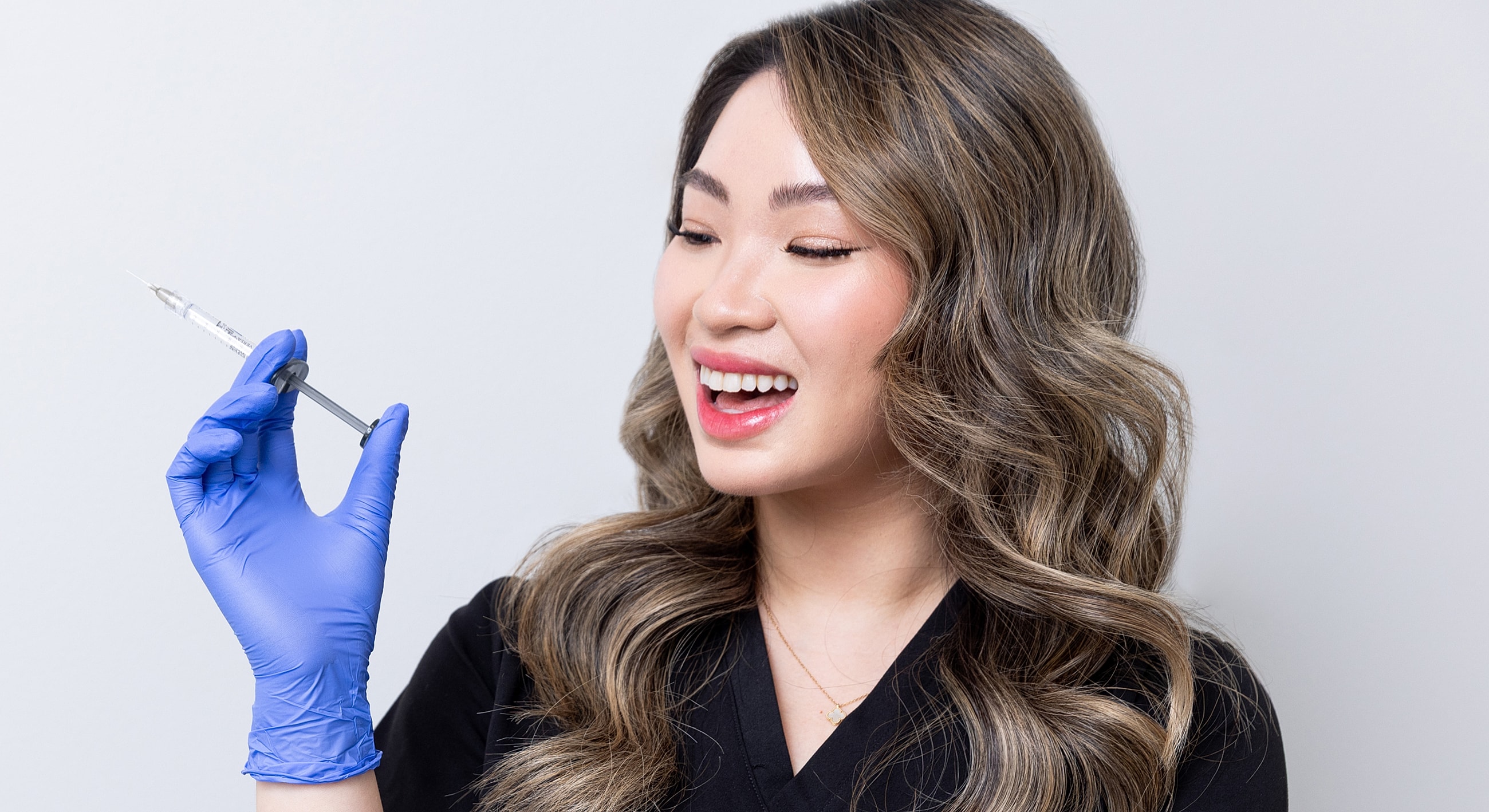 Person with syringe, smiling in medical setting.