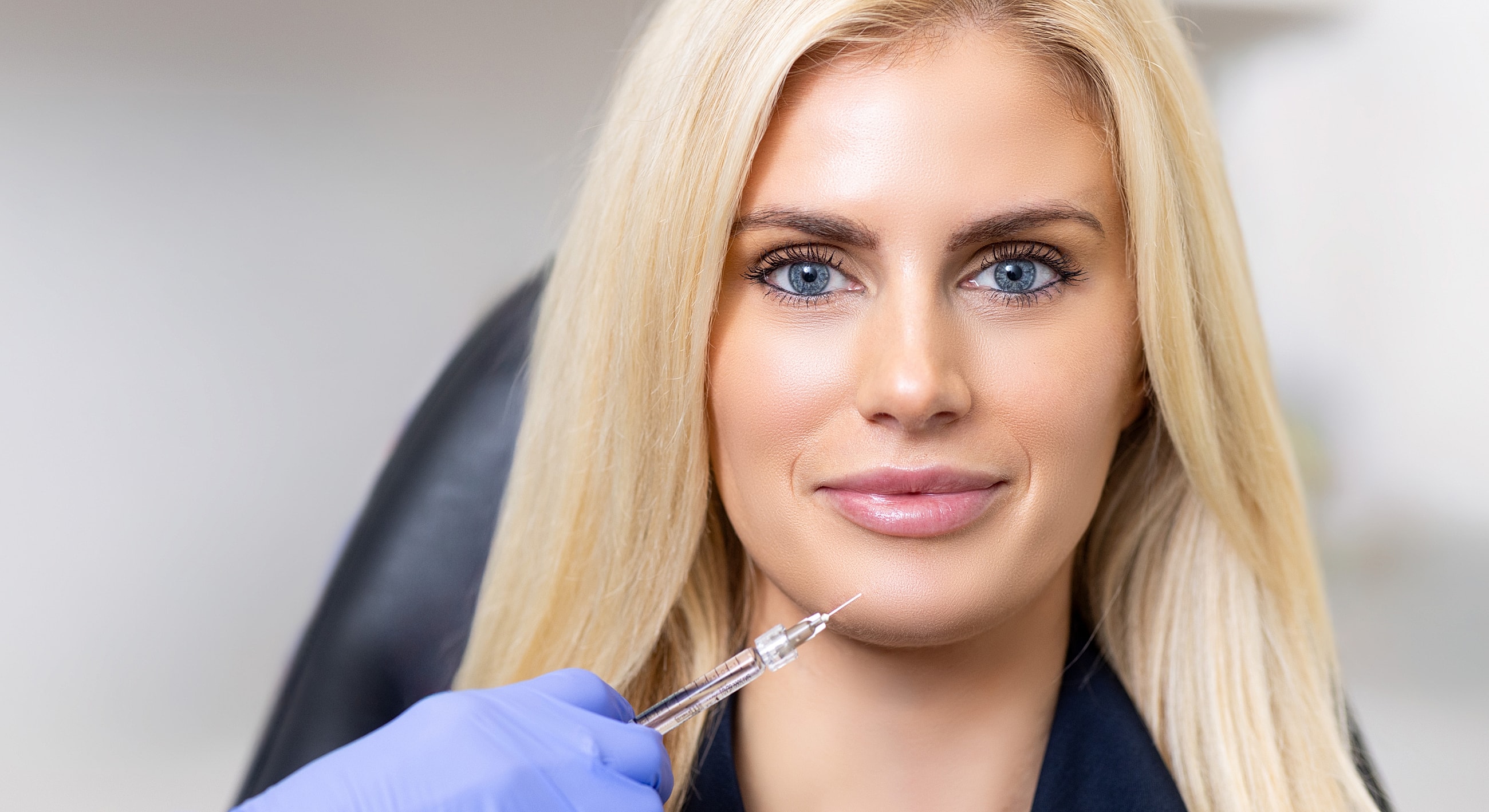 Cosmetic treatment preparation with syringe and patient.